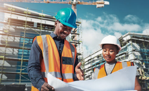 Shot of a young man and woman going over building plans at a construction site.